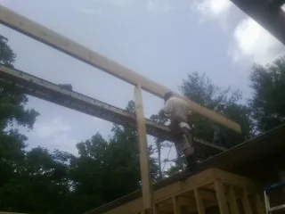 Carpenter setting a ridge beam over a new addition frame — Ice Dam Removal by Roofing Brothers in Griffin