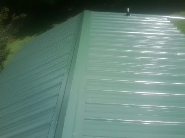 New green metal panels meeting at the ridge of a roof — Flat Roof Repair work by our crew in Griffin