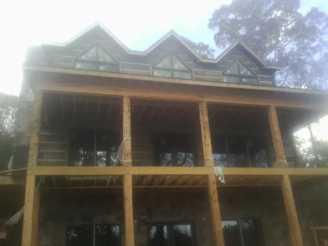 Dormers and porch framing on a large log home under construction — Roof Coating work by our crew in Griffin