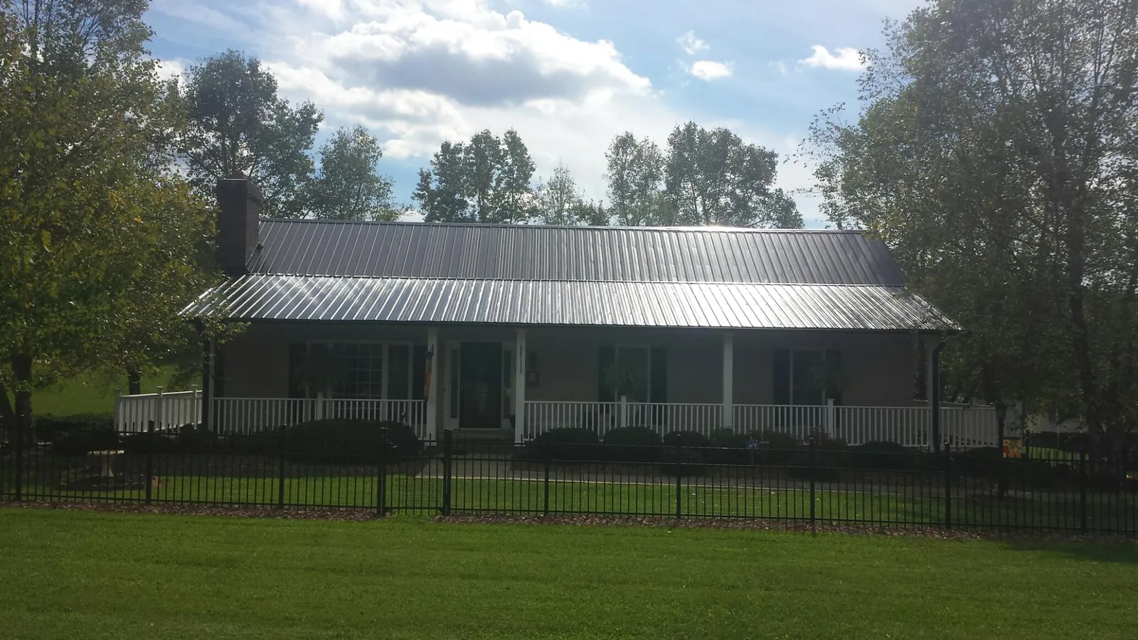 Gray metal roof on a brick ranch with a full width front porch — Gutter Guard Installation work by our crew in Griffin